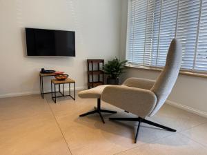 a living room with a chair and a flat screen tv at Beach House Rodine - free parking & bikes in Scheveningen
