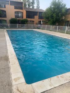 a blue swimming pool in front of a building at Studio village 9 in Arles