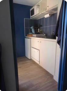 a kitchen with white cabinets and a blue wall at Studio village 9 in Arles