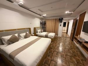 a hotel room with two beds and a television at Prestige by Alnoor in Skardu