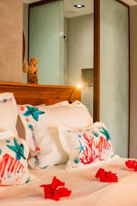a bed with white pillows and red flowers on it at Pousada de Charme Villa Italiana - Pé na Areia in São Miguel dos Milagres +74 photos