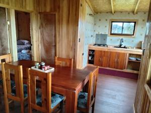 a dining room with a wooden table and a kitchen at Cabañas almendra in Quellón