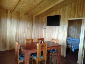 a dining room with a wooden table and chairs at Cabañas almendra in Quellón