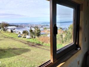 a window with a view of a field at Cabañas almendra in Quellón +1 photo