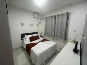a small white bedroom with a bed and a shower at Refúgios de Itaúna in Saquarema