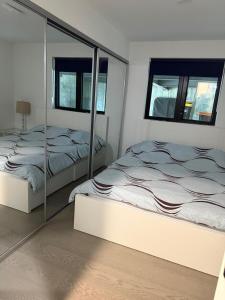 two beds in a white room with mirrors at 2BDRM-Kitchenette-BBQ-Smart TV-4-5Guest in West Vancouver