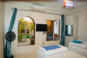 a room with two beds and a tv and a window at Tranquil Villa, private Pool, Garden, Wifi, Fayoum in Qaryat at Ta‘mīr as Siyāḩīyah