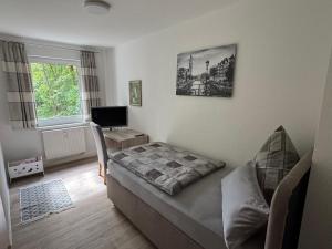 a bedroom with a bed and a desk and a television at Fewo Am Poetenteich in Jänkendorf