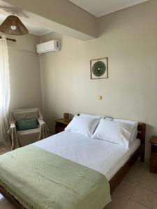a bedroom with a large white bed and a chair at SunKipos in Paleros
