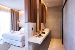 a bathroom with a bed and a sink in a room at Kastri Beach Suites in Faliraki