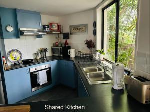 a small kitchen with blue cabinets and a sink at Nicole Guest House - Private Room & Bathroom - 6kms from City in Brisbane