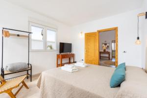 a white room with a bed and a television at Eden Rentals Oasis Boho 1 in Las Galletas