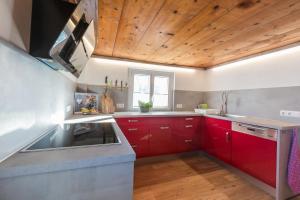 a kitchen with red cabinets and a wooden ceiling at Haus No 60 Kleinwalsertal in Hirschegg