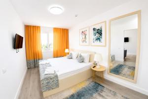 a white bedroom with a large bed and a mirror at Spring Holiday Resort in Neptun