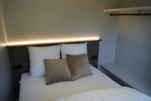 a bed with white sheets and pillows in a room at Tiny House ALPEA in Fillinges