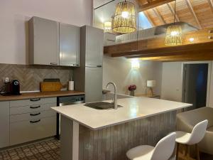 a kitchen with white cabinets and a sink and chairs at Casas Morgado in Valada