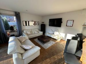 a living room with white furniture and a tv at Haus-36 in Neuss