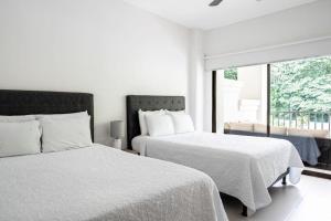 a white bedroom with two beds and a window at Jaco Bay 1202 in Jacó +38 photos