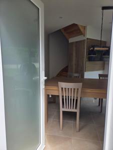 a dining room with a wooden table and a chair at Le Petit L Orée des Bois in Blainville-sur-lʼEau