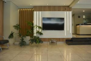a large flat screen tv on a wall in a lobby at Hotel Gênova BC in Balneário Camboriú