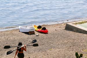 a woman standing on a beach with two kayaks on the water at Lakefront Villa with Beach Access & Infinity Pool in San Pedro La Laguna