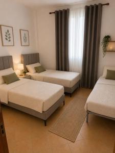 a room with three beds and a window at Vacation house villa roni in Durrës