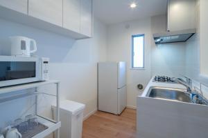 a white kitchen with a sink and a refrigerator at treehouse - Vacation STAY 22128 in Nagoki