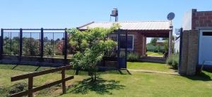 a house with a fence and a tree in the yard at Los 3 Gurises in Gualeguay