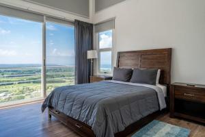 a bedroom with a large bed and large windows at Casa La Cima in Playa Hermosa