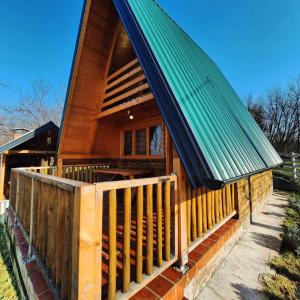 a cabin with a green roof and a wooden fence at Medeni brijeg in Donji Potok