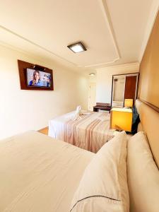 a hotel room with two beds and a tv on the wall at Akirá Pousada in Aquiraz
