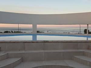 a swimming pool with a view of the ocean at St Helena Bay Hotel in St. Helena Bay