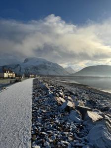 a road next to a body of water with mountains at 15 By The Shore in Caol