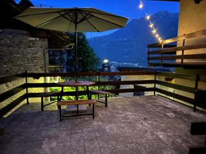 a table and a bench with an umbrella on a balcony at Casa Vanda in Châtillon