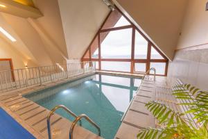 a pool in a building with a large window at Wyndham Puerto Varas Pettra in Puerto Varas