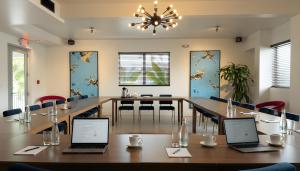 a conference room with a long table with two laptops on it at The Vagabond Hotel Miami in Miami +69 photos
