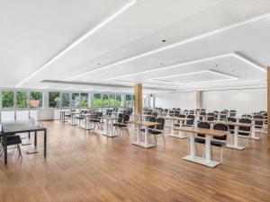 an empty room with tables and chairs and windows at Movenpick Resort and Spa Fruske Terme in Vrdnik +230 photos