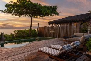 a deck with a chair and a couch and a pool at Casa do Amor Caraíva in Caraíva
