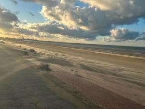 a sandy beach with a cloudy sky and the ocean at Charmant studio vue dégagée à 300m de la plage in Dunkerque