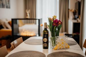 a bottle of wine sitting on a table with flowers at Apartmány Esprit in Dolný Kubín