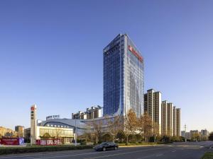 a car driving down a road in front of a tall building at Pullman Huai'an in Huai'an