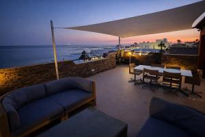 a patio with a couch and a table and chairs at Espectacular ático en 1°linea playa in Rota