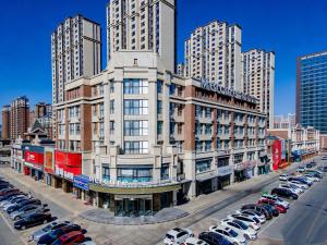 a large building with cars parked in a parking lot at Mercure Huhhot Economic Zone in Hohhot