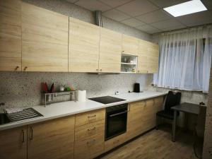 a kitchen with wooden cabinets and a table with a chair at Pilnų namų bendruomenė in Panara +11 photos