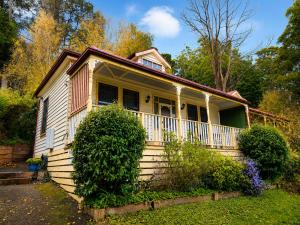 a small white house with a porch on a yard at Charnwood Cottages in Warburton