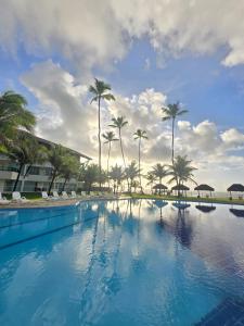 a large swimming pool with palm trees in the background at Best location of the development, ground floor seafront in Porto De Galinhas