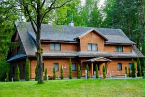 a large wooden house in the middle of a yard at Pilnų namų bendruomenė in Panara