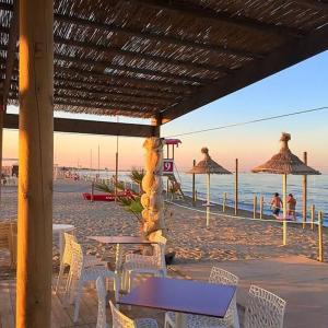 a beach with chairs and tables and umbrellas at Casa Ezio beach&relax in Chioggia