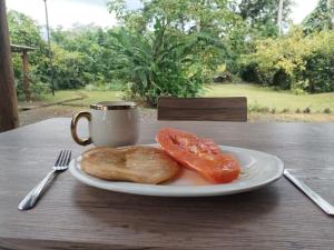 a plate with bread and tomatoes on a table with a cup at El Carao in Talamanca