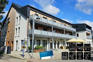 a large white building with signs in front of it at ENJOYHARRACHOV - Atraktivní slunný klimatizovaný apartmán 24 v centru Harrachova s velkou terasou, saunou, parkováním, Wifi-WLAN, SAT, herní konzolí, Netflix zdarma a možností dobíjení auta jen 150m od lanovky in Harrachov